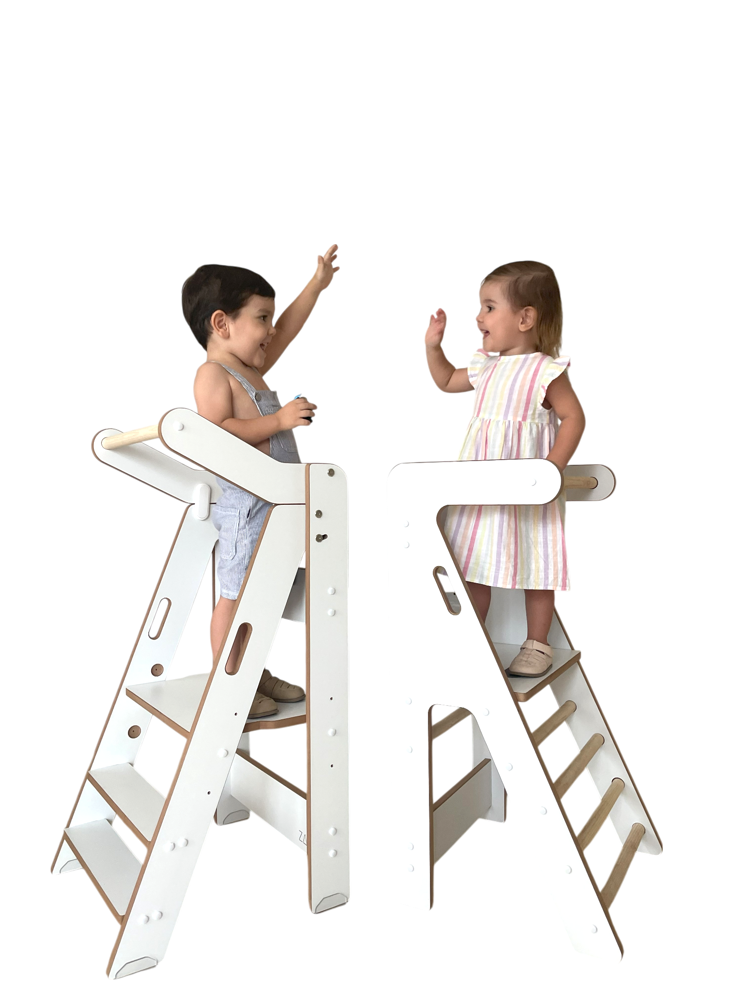 Zalu e Izar, dos niños pequeños sobre sus torres de aprendizaje ZALU de color blanco y pino, en un saludo enérgico.