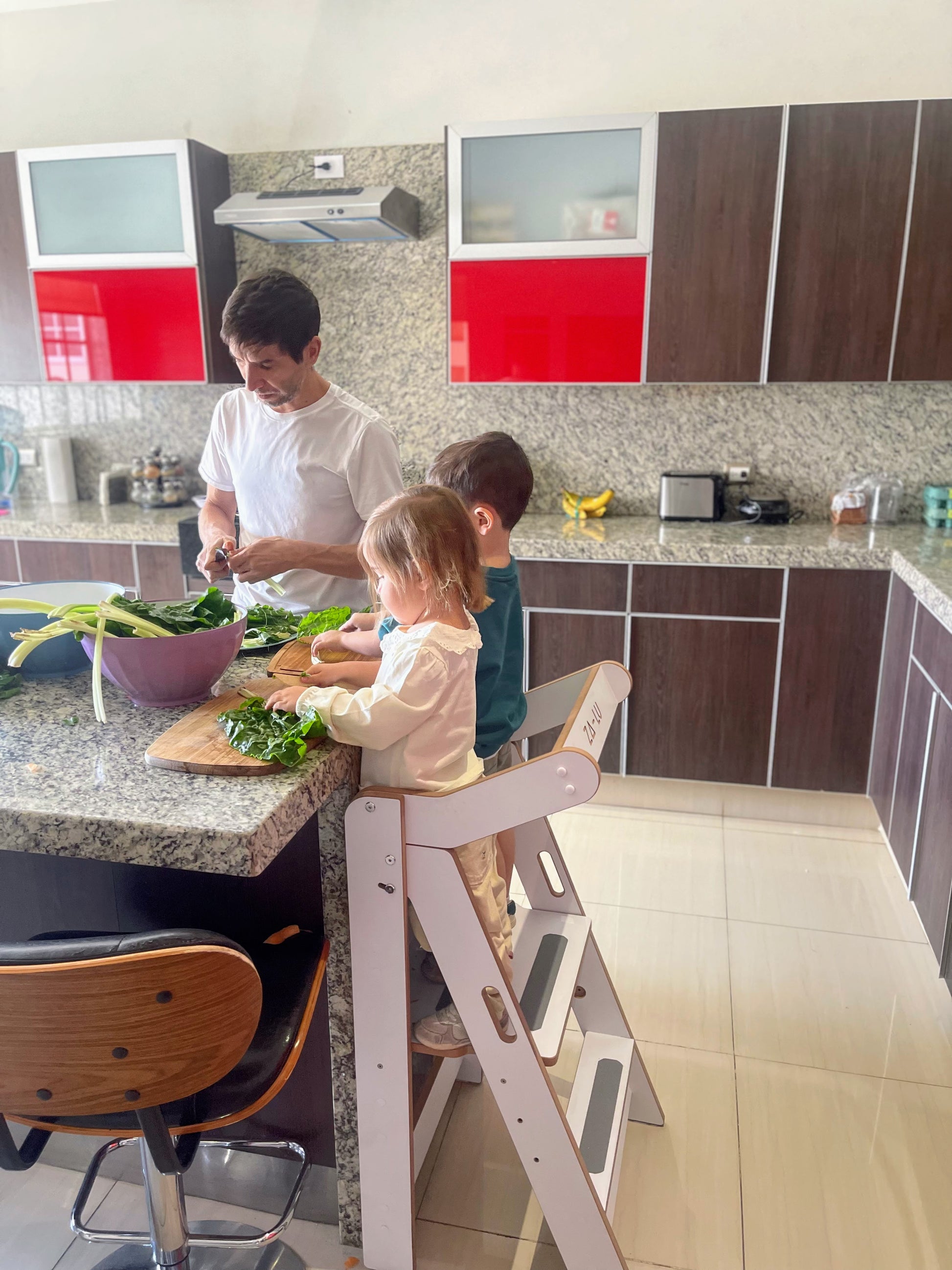 foto real de un papá con sus hijos cocinando con la torre de aprendizaje montessori zalu