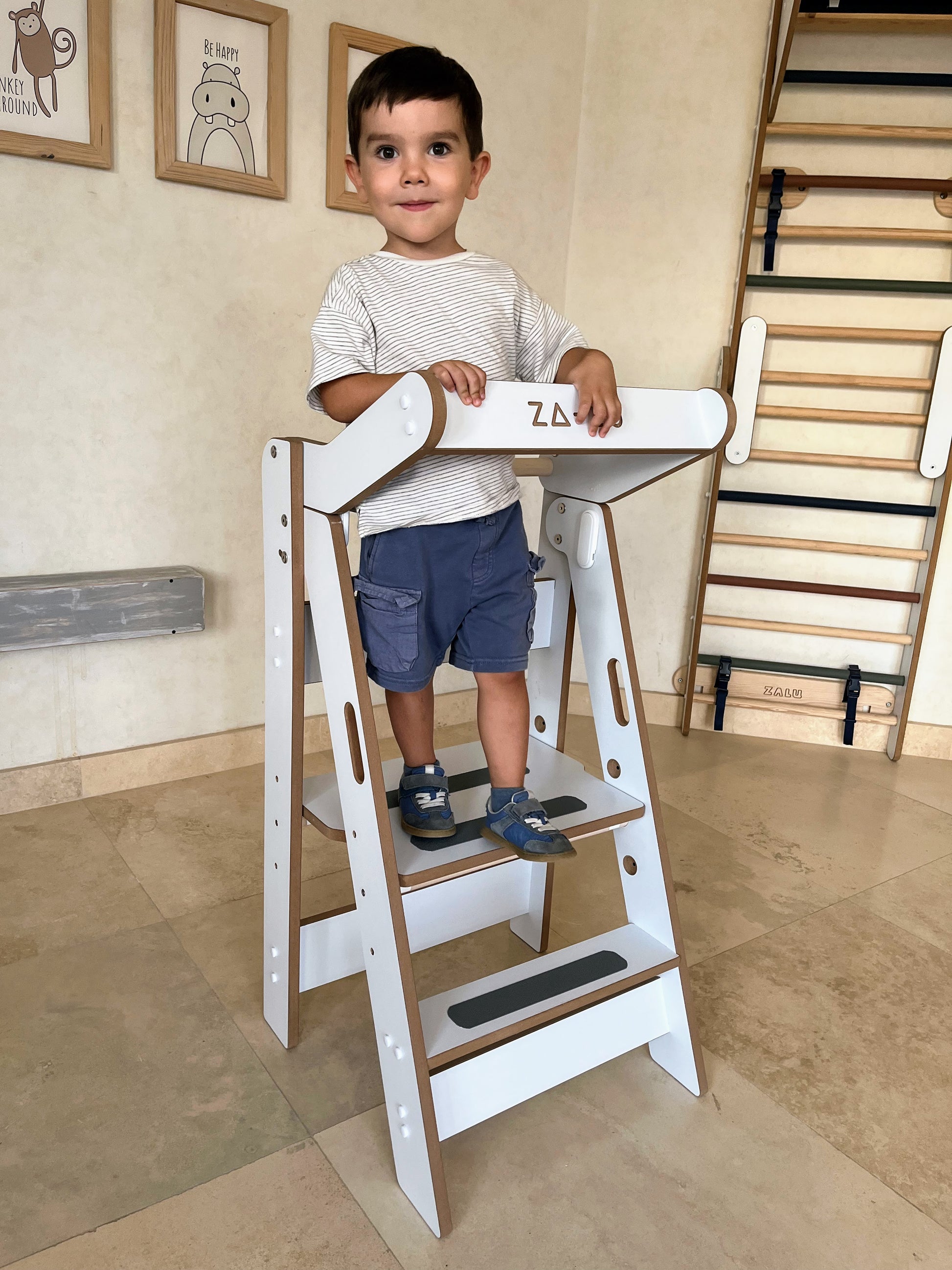 nio subido en la torre de aprendizaje montessori zalu mirando a cámara